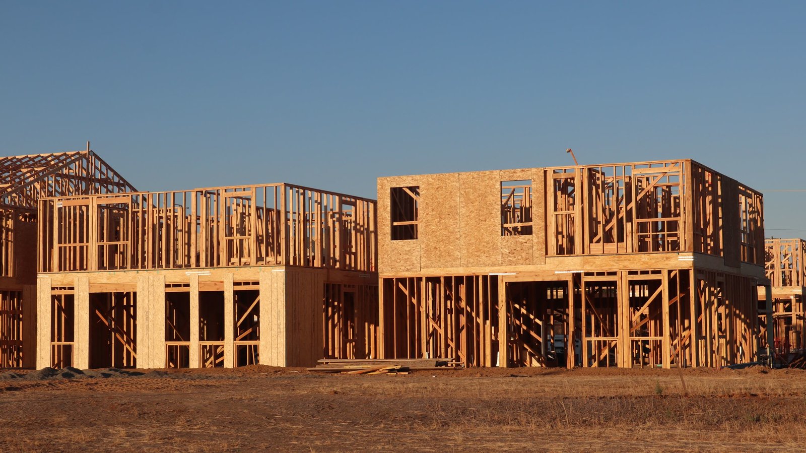 Two-story homes in wood framing at golden hour on a graded site